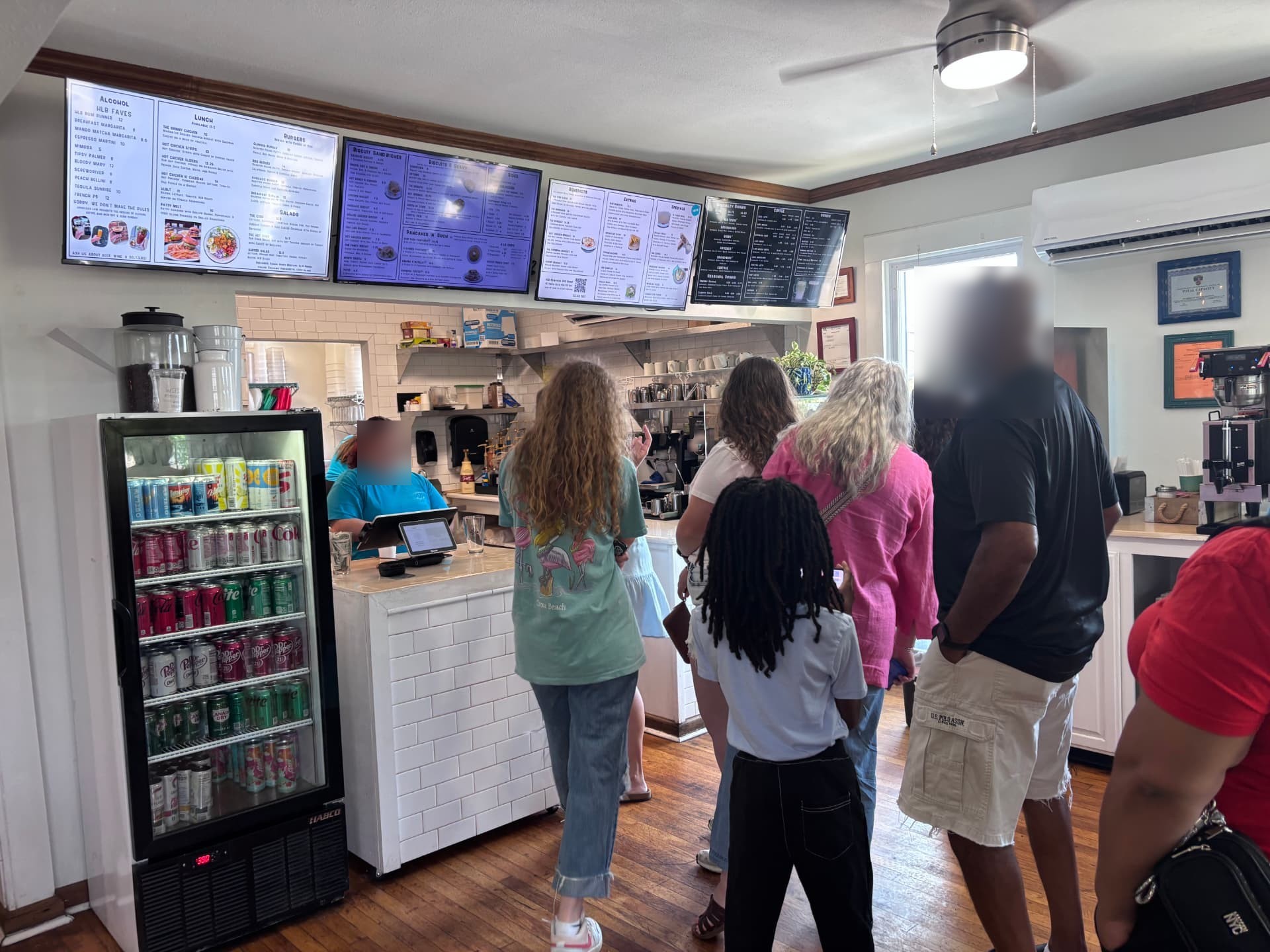 Customers ordering at the front counter inside Hillcrest Little Bakery, with the pastry case and menu board behind the register
