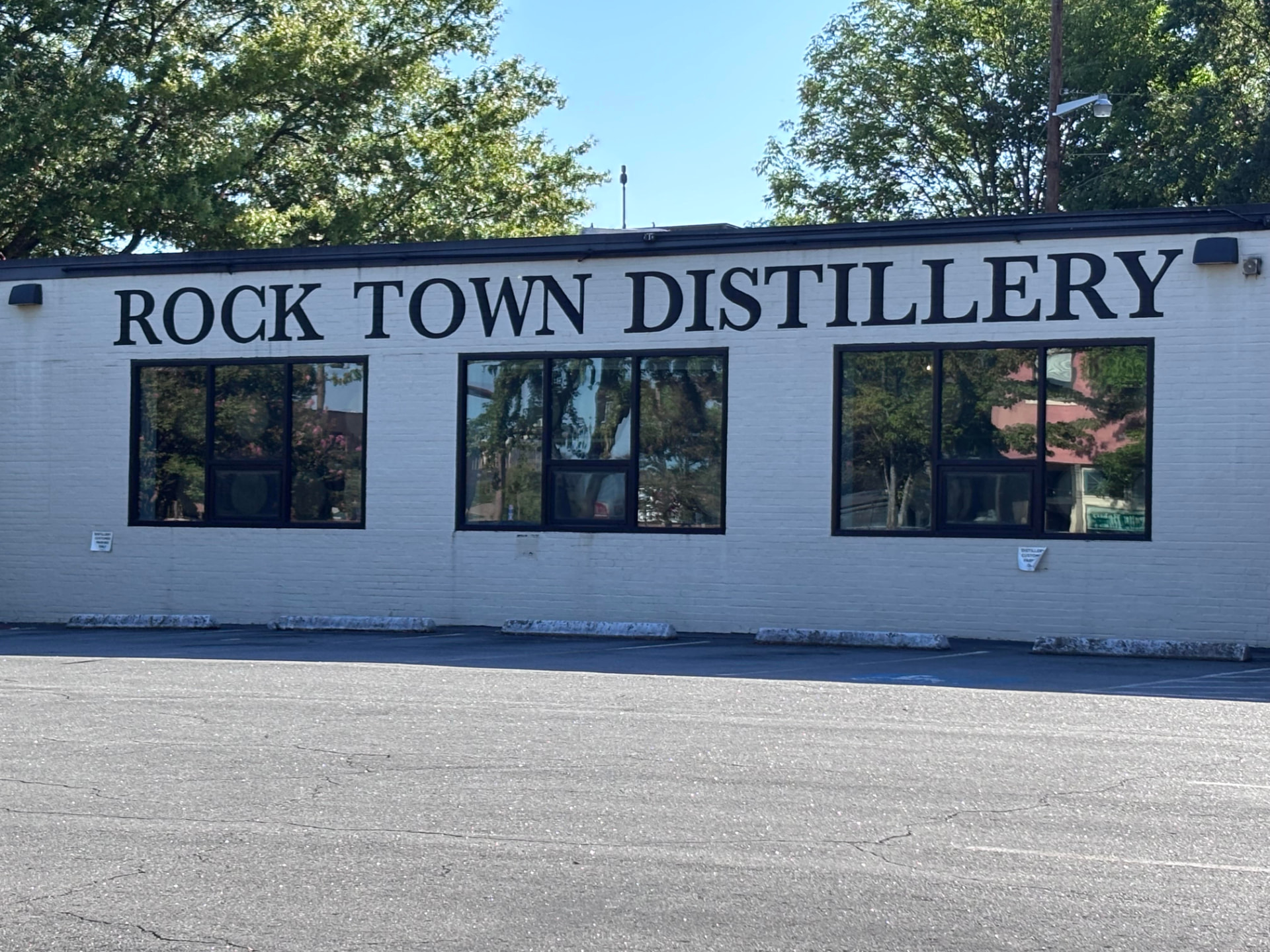 The white brick exterior of Rock Town Distillery in Little Rock, with bold black lettering across the facade and a parking lot out front