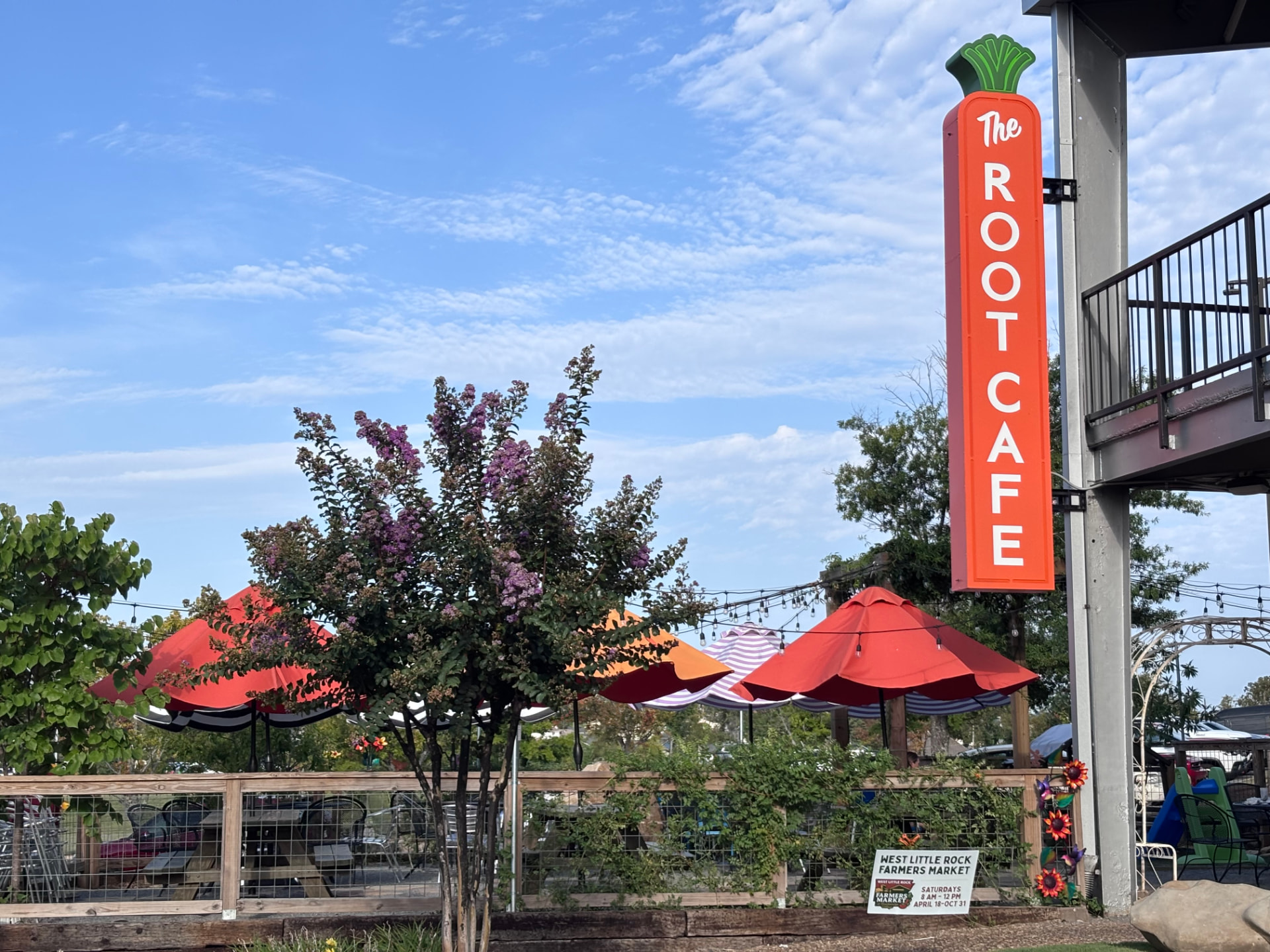 The Root Café's tall orange carrot-shaped sign above the shaded patio at its West Little Rock location in Breckenridge Village